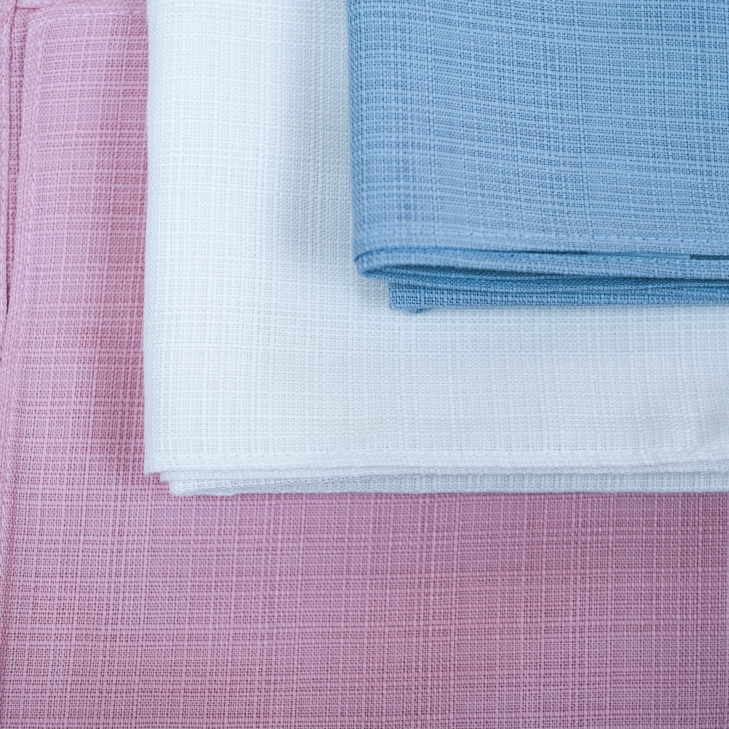Close-up of pink, white, and blue textured fabric swatches.