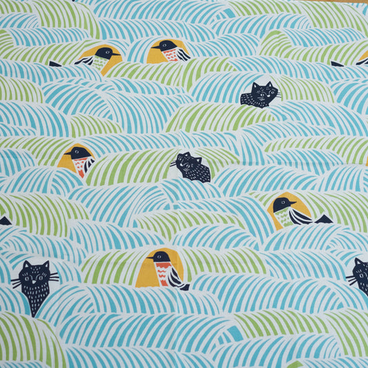 Close-up of a furoshiki cloth with birds and cats on a blue and green background