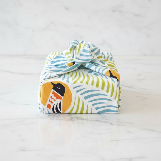Colorful fabric pouch with bird design on a white marble surface
