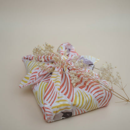 Colorful fabric bundle with dried flowers on a beige background
