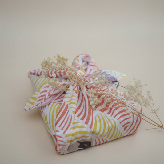 Colorful fabric bundle with dried flowers on a beige background