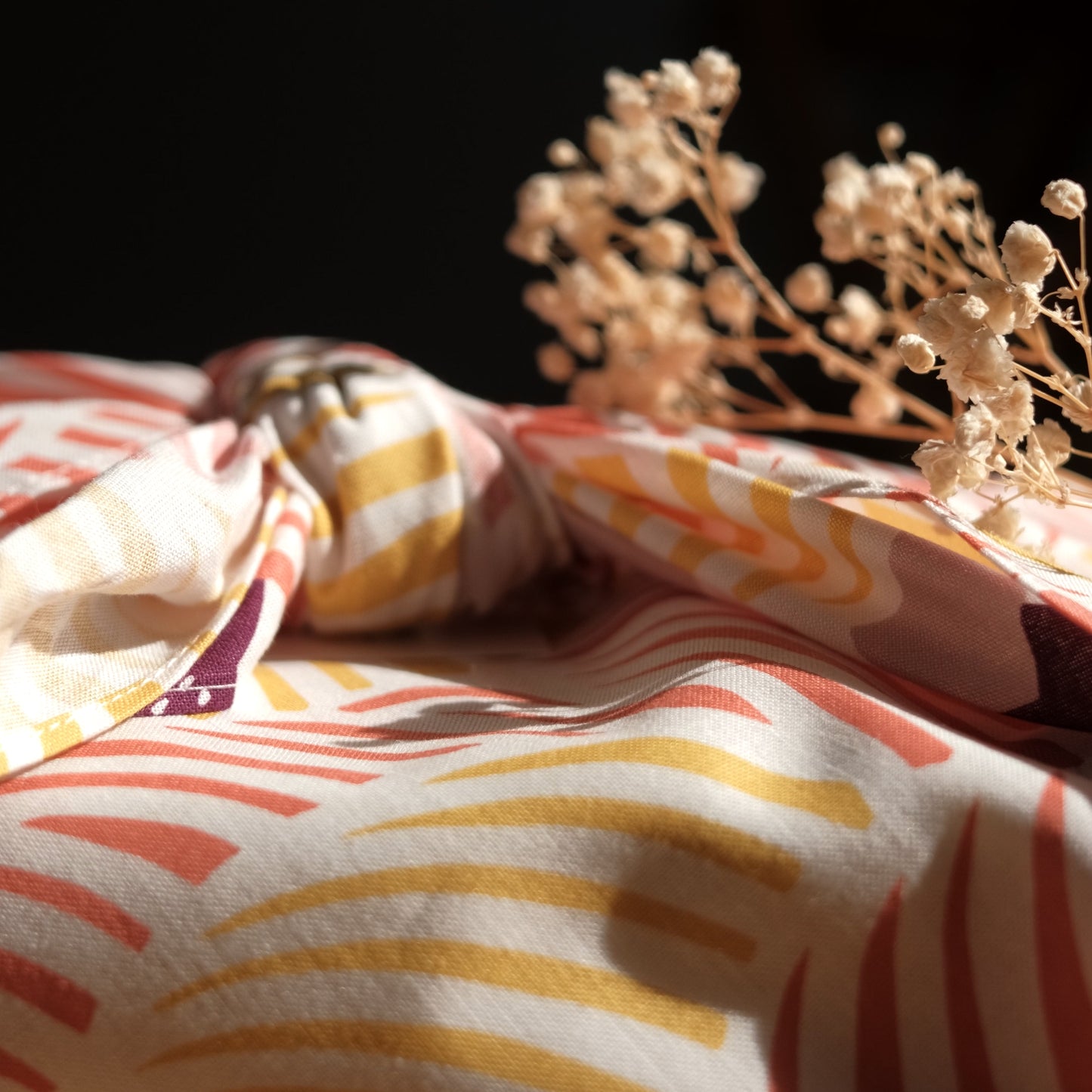 Furoshiki cloth with wavy pattern and dried flowers on a dark background
