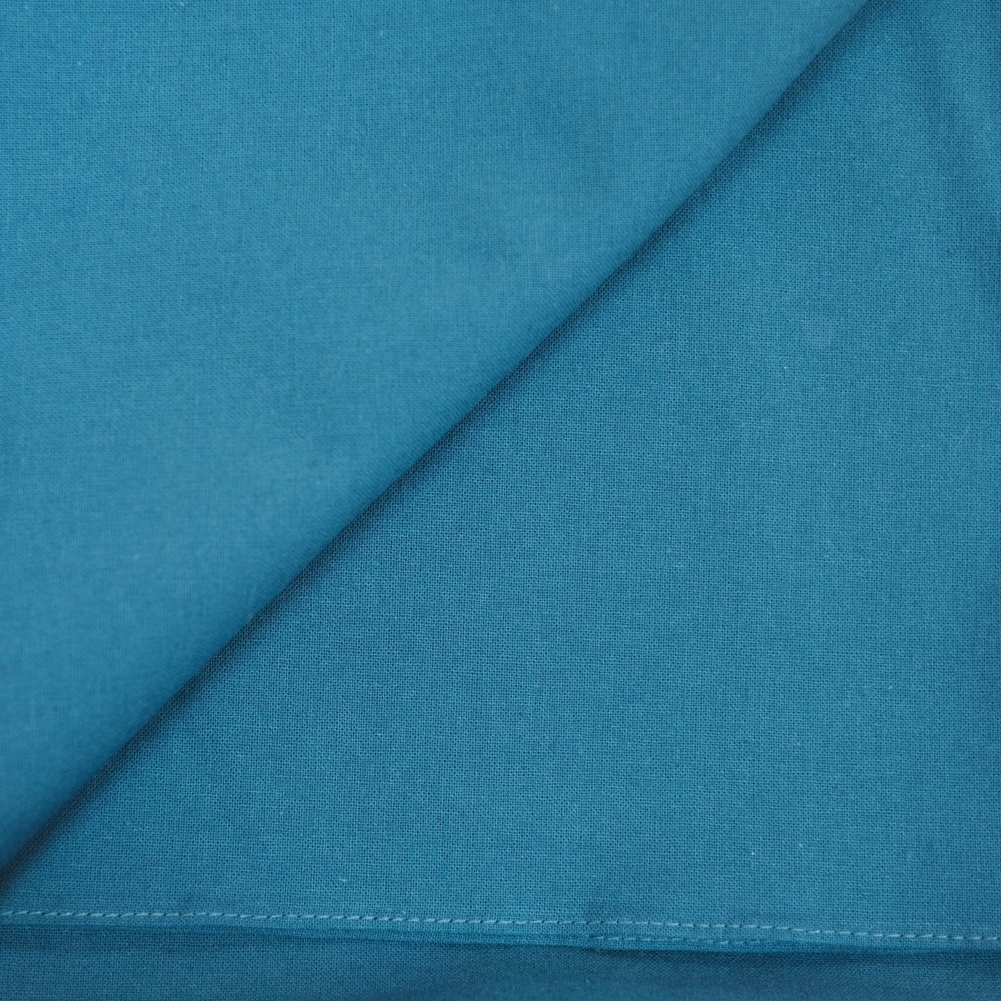 Teal furoshiki fabric with a diagonal seam and stitching detail