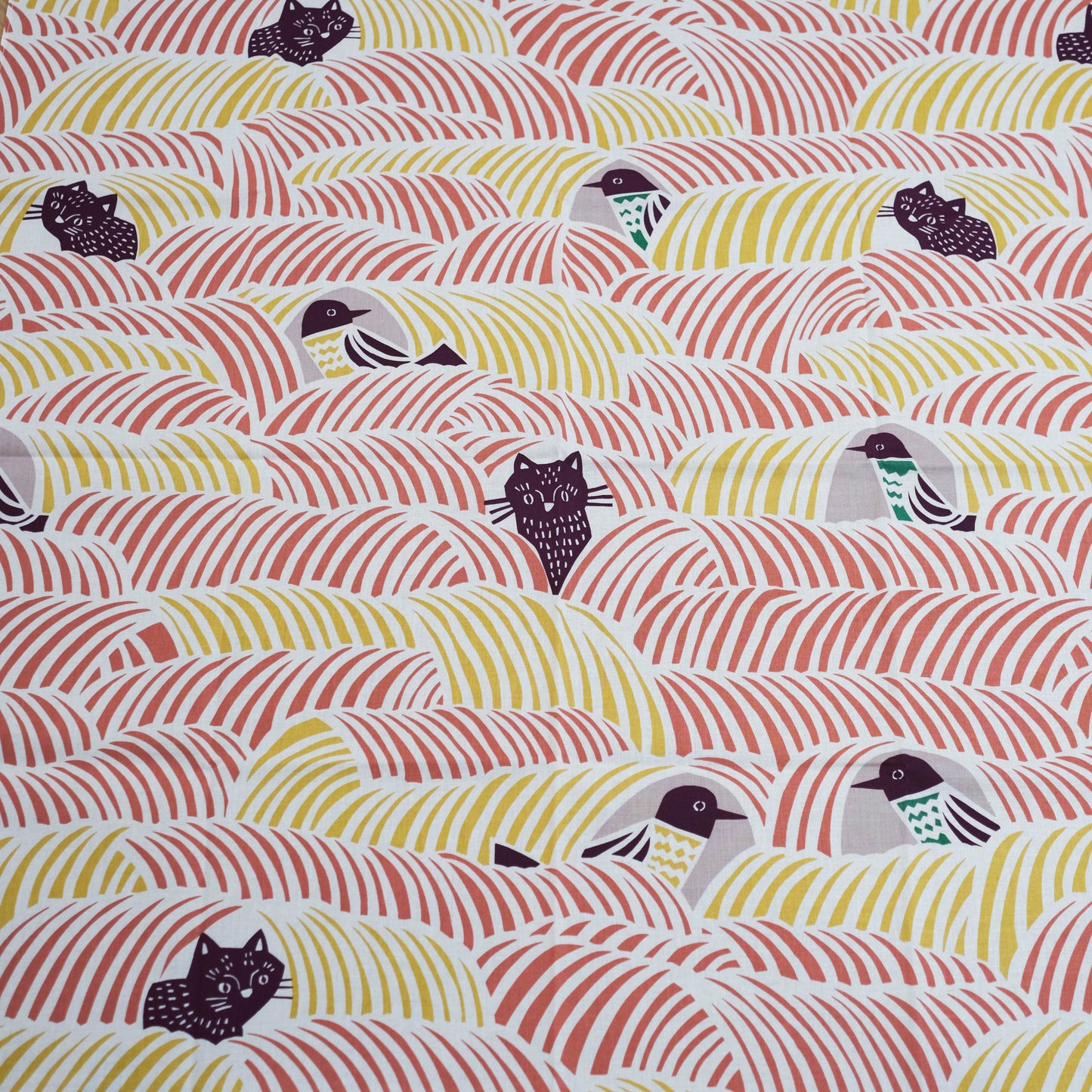 Close-up of a furoshiki cloth with birds and cats on a pink and yellow background