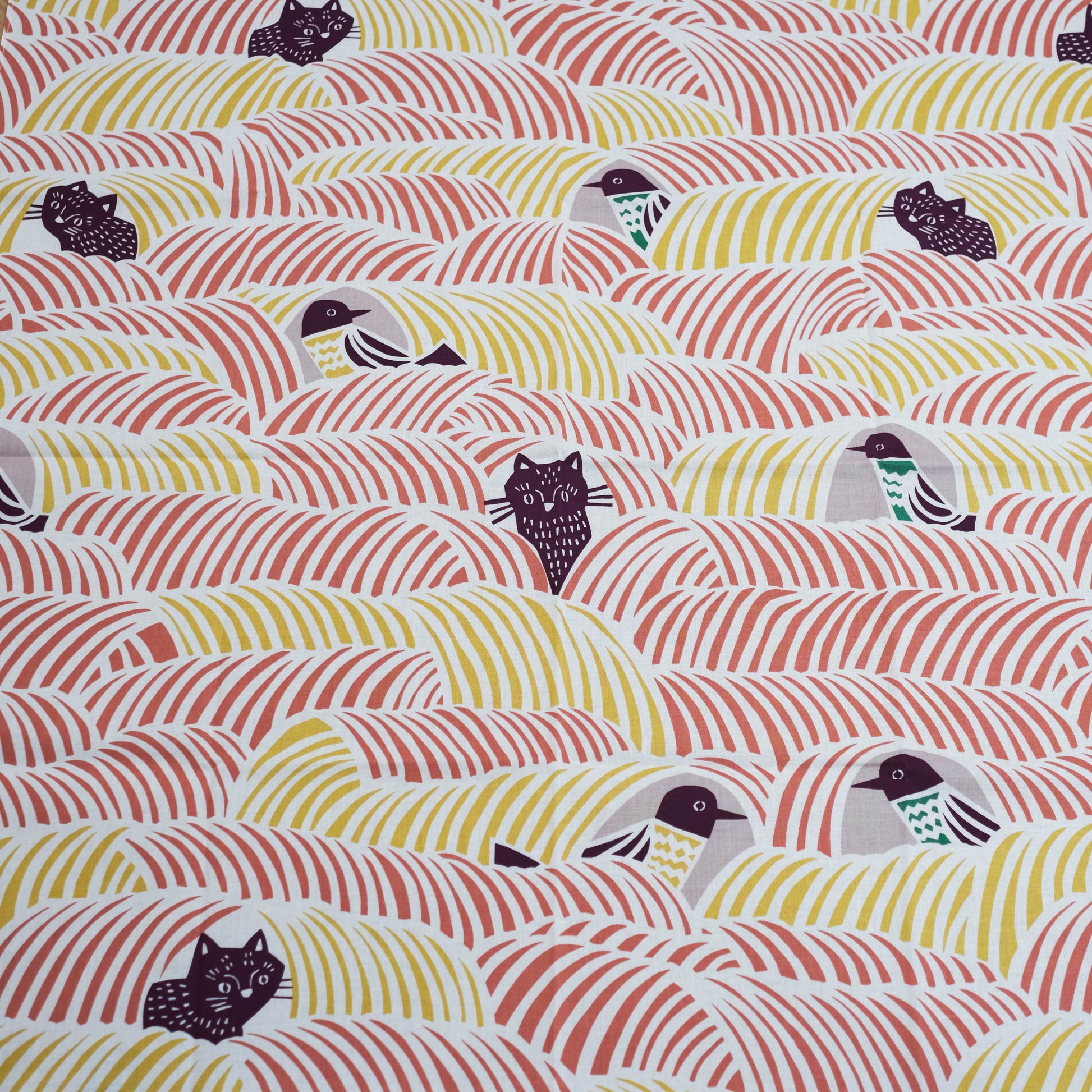 Close-up of a furoshiki cloth with birds and cats on a pink and yellow background