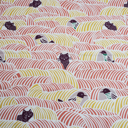Close-up of a furoshiki cloth with birds and cats on a pink and yellow background