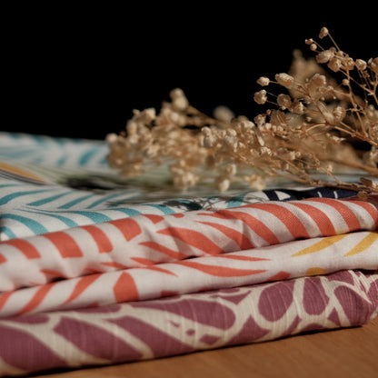 Stack of patterned fabrics with dried flowers on a dark background