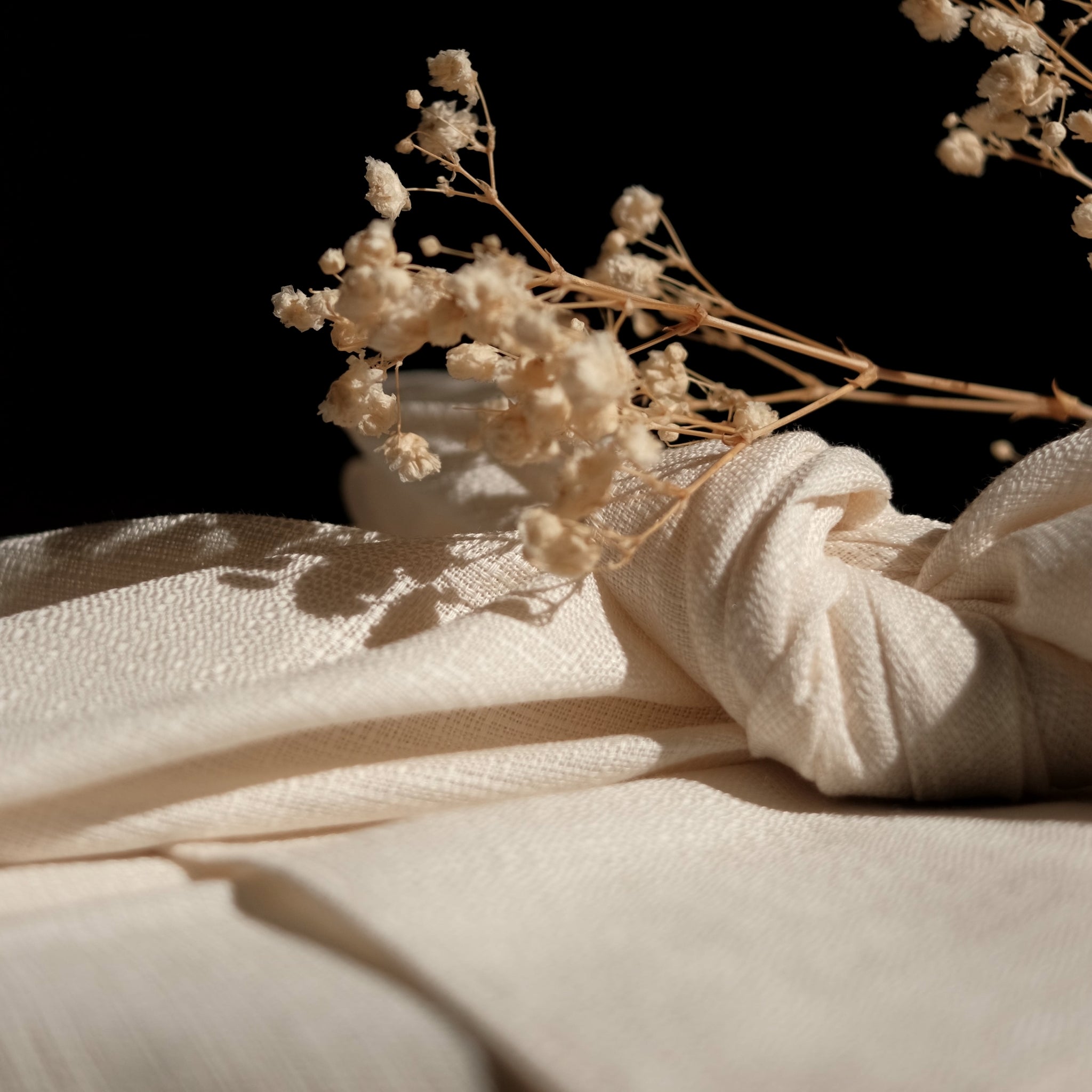 Dried flowers on a textured beige furoshiki cloth with a dark background